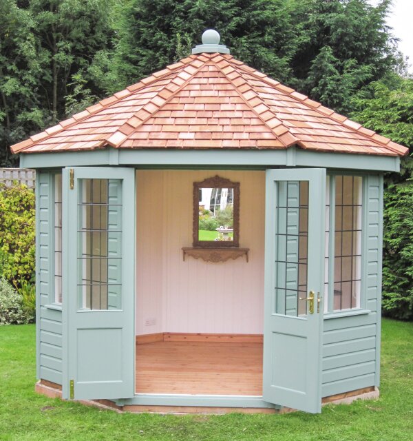 Wiveton with cedar shingle roof Pale green octagonal summerhouse with open double doors and a warm-toned cedar shingle roof.